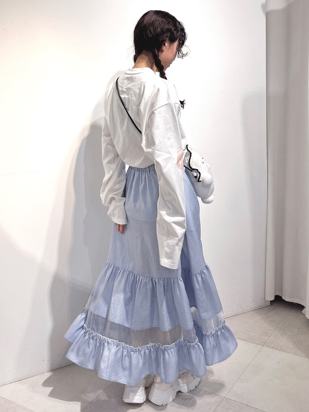 ホワイト系のショルダーバッグ、ホワイト系のTシャツ/カットソー、ブルー系のスカートを着用したレディースの冬コーディネートの3枚目の写真