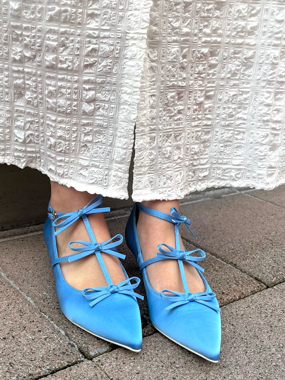 ホワイト系のワンピース、ブルー系のパンプスを着用したレディースの冬コーディネートの5枚目の写真