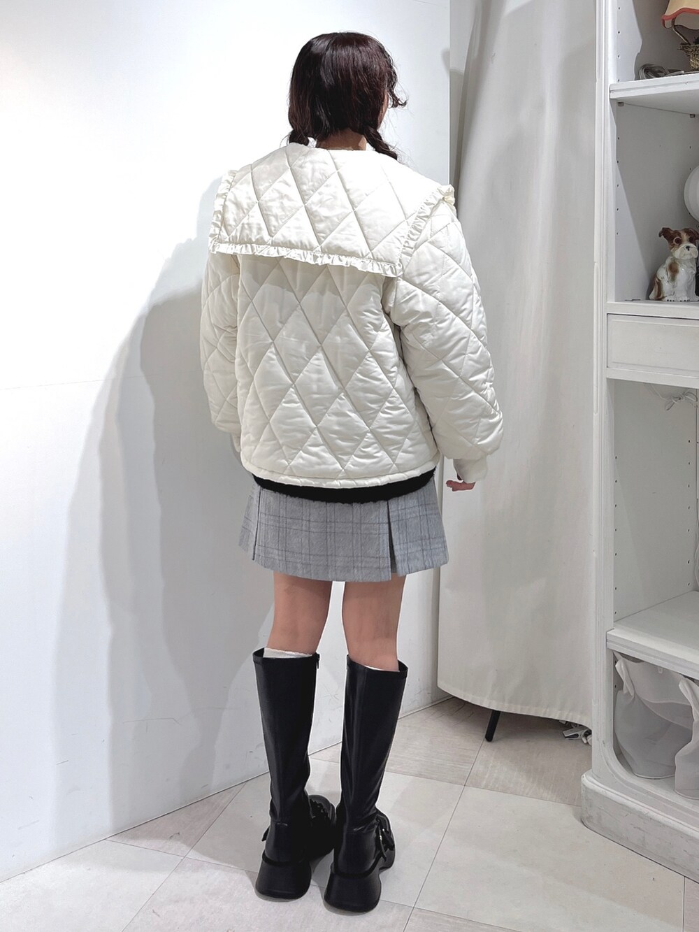 ブラック系のニット/セーター、ホワイト系のダウンジャケット/コート、グレー系のスカートを着用したレディースの冬コーディネートの2枚目の写真