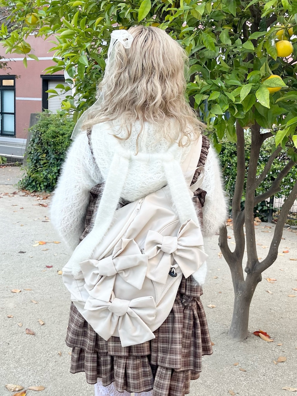 ホワイト系のニット/セーター、ブラウン系のワンピース、ベージュ系のショルダーバッグを着用したレディースの秋コーディネートの7枚目の写真