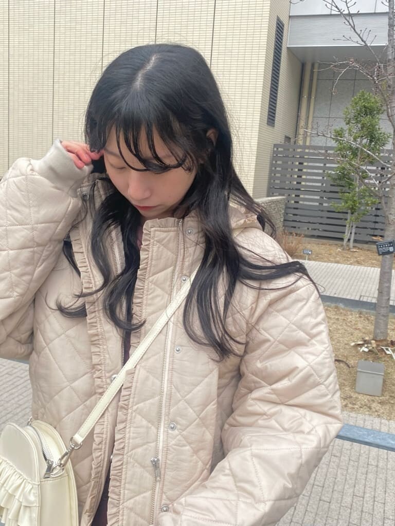 ホワイト系のナイロンジャケット、ホワイト系のショルダーバッグ、レッド系のワンピースを着用したレディースの冬コーディネートの3枚目の写真