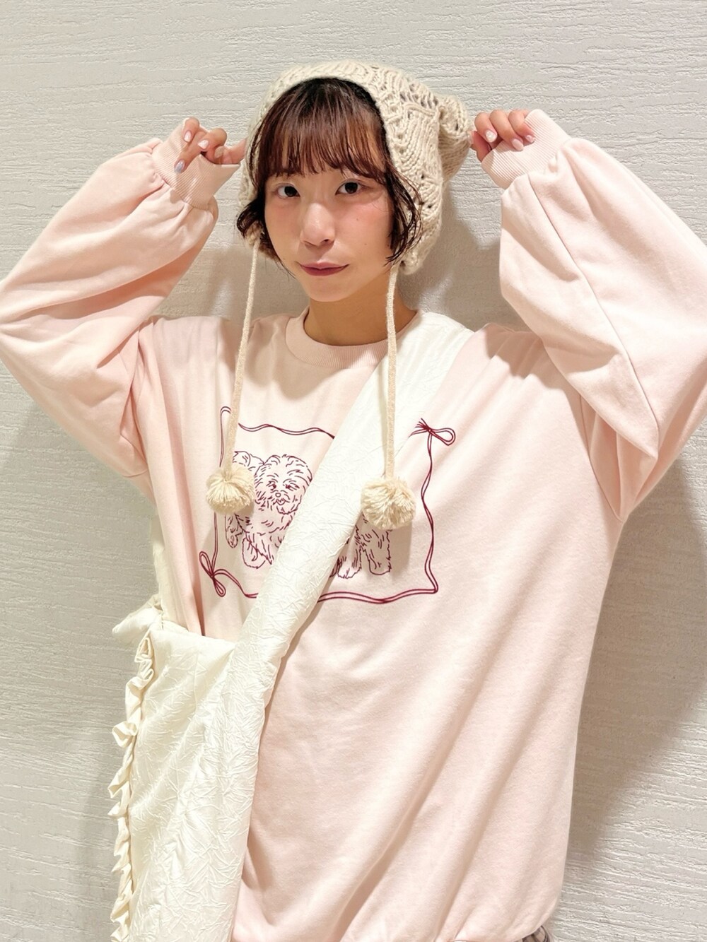 ピンク系のスウェット、ベージュ系のスカート、ホワイト系のトートバッグを着用したレディースの秋コーディネートの5枚目の写真