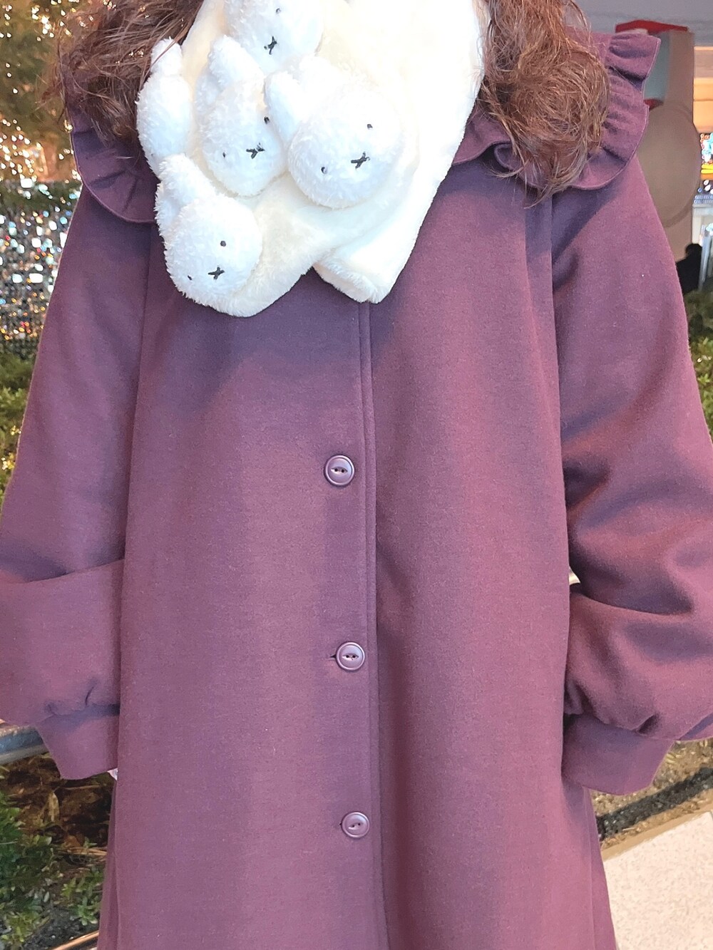 レッド系のチェスターコート、ホワイト系のニット/セーター、ホワイト系のスウェットを着用したレディースの冬コーディネートの6枚目の写真