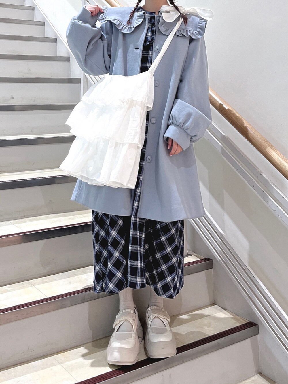 ブルー系のチェスターコート、ブルー系のワンピース、ホワイト系のショルダーバッグを着用したレディースの冬コーディネートの6枚目の写真