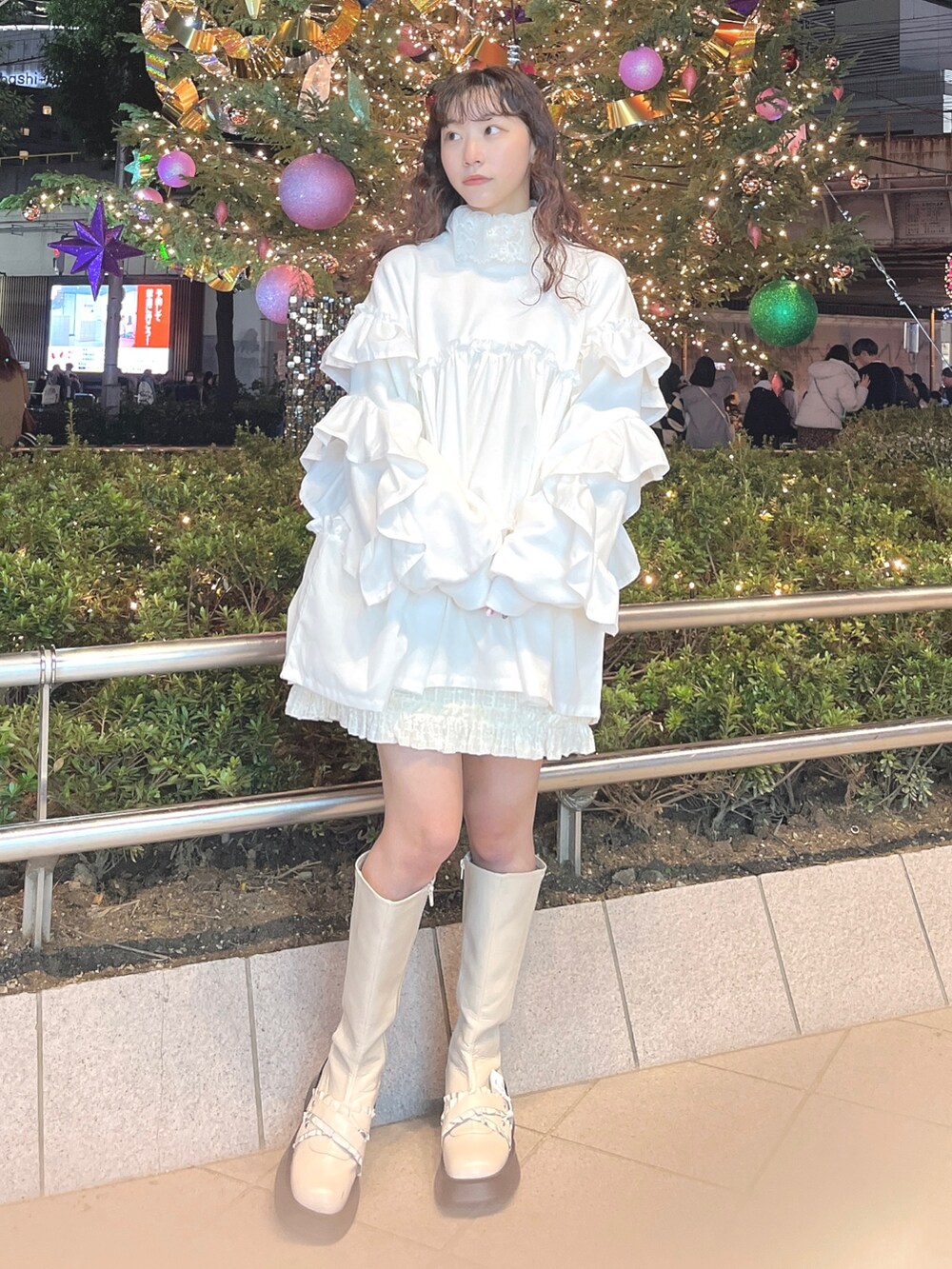 レッド系のチェスターコート、ホワイト系のニット/セーター、ホワイト系のスウェットを着用したレディースの冬コーディネートの7枚目の写真