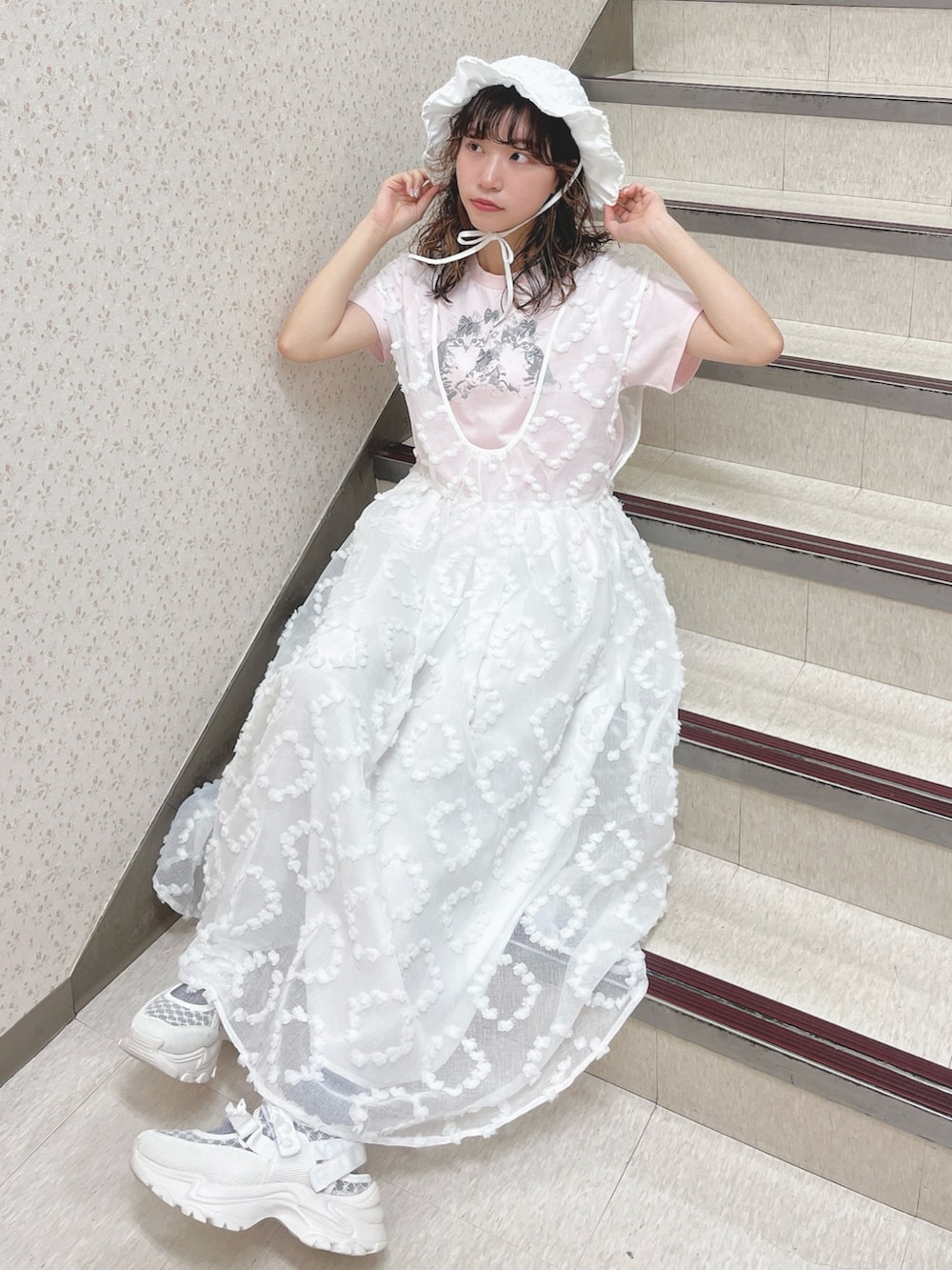 ピンク系のTシャツ/カットソー、ホワイト系のジャンパースカート、ホワイト系のスニーカーを着用したレディースの夏コーディネートの5枚目の写真