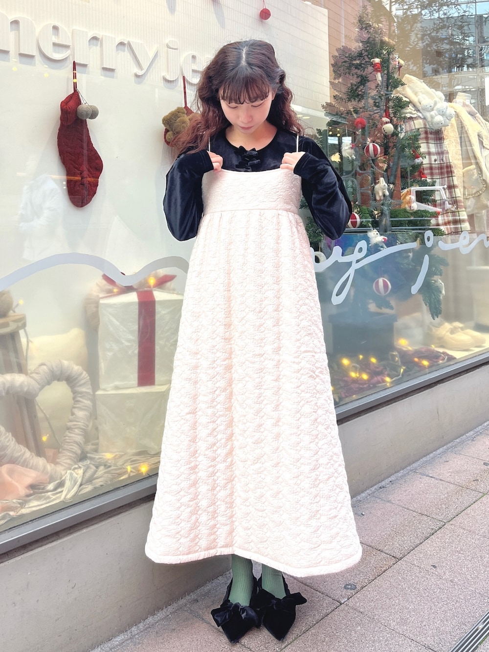 ピンク系のチェスターコート、ブラック系のカーディガン/ボレロ、ホワイト系のワンピースを着用したレディースの冬コーディネートの5枚目の写真