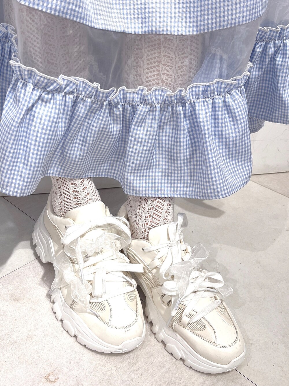 ホワイト系のショルダーバッグ、ホワイト系のTシャツ/カットソー、ブルー系のスカートを着用したレディースの冬コーディネートの10枚目の写真