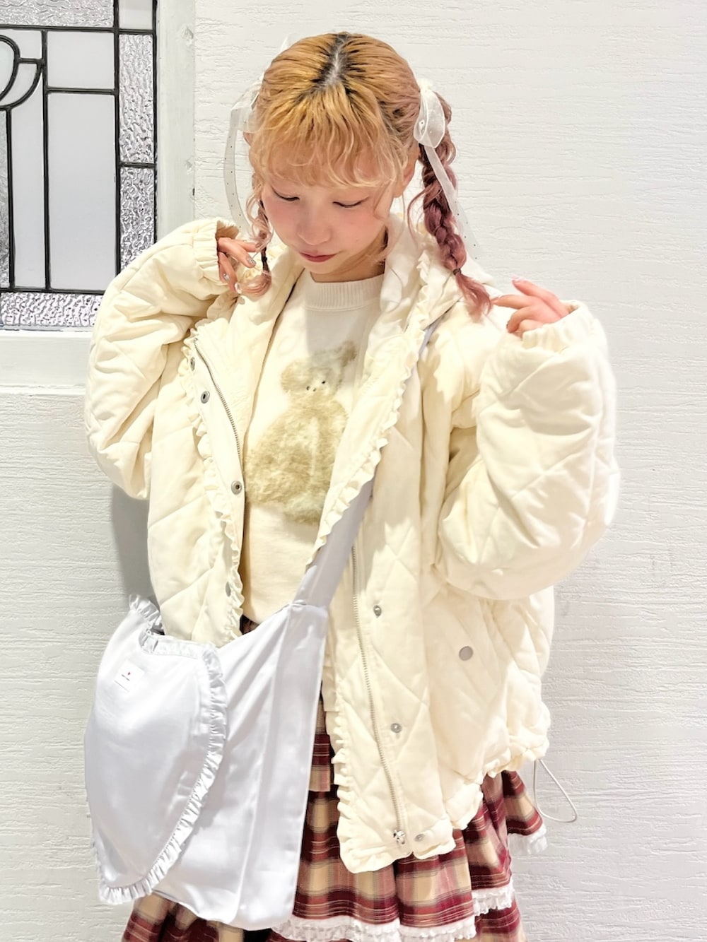 ホワイト系のダウンジャケット/コート、ホワイト系のニット/セーター、ブルー系のショルダーバッグを着用したレディースの冬コーディネートの5枚目の写真