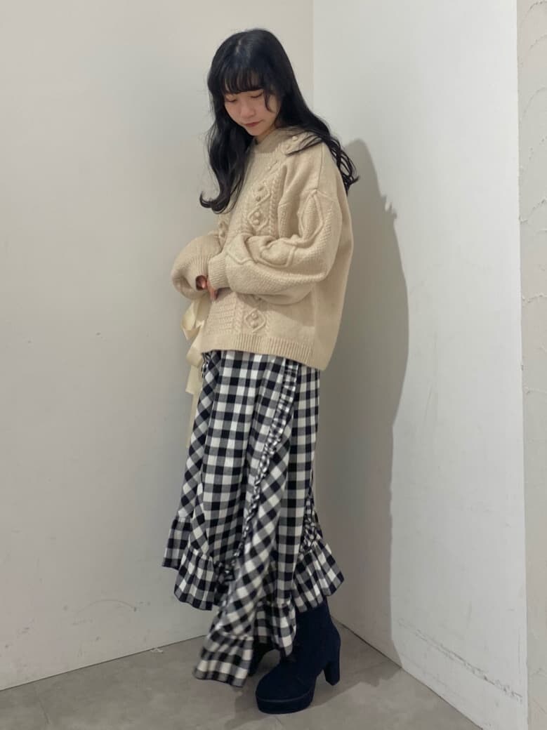 ブラック系のスカート、ブルー系のブーツ、ホワイト系のニット/セーターを着用したレディースの秋コーディネートの2枚目の写真