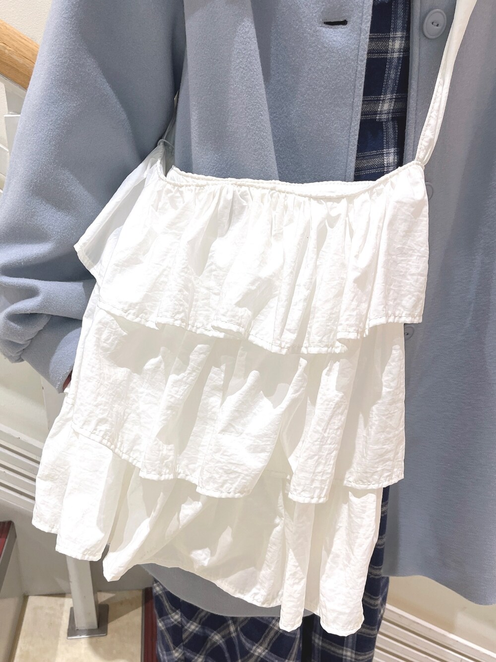 ブルー系のチェスターコート、ブルー系のワンピース、ホワイト系のショルダーバッグを着用したレディースの冬コーディネートの9枚目の写真