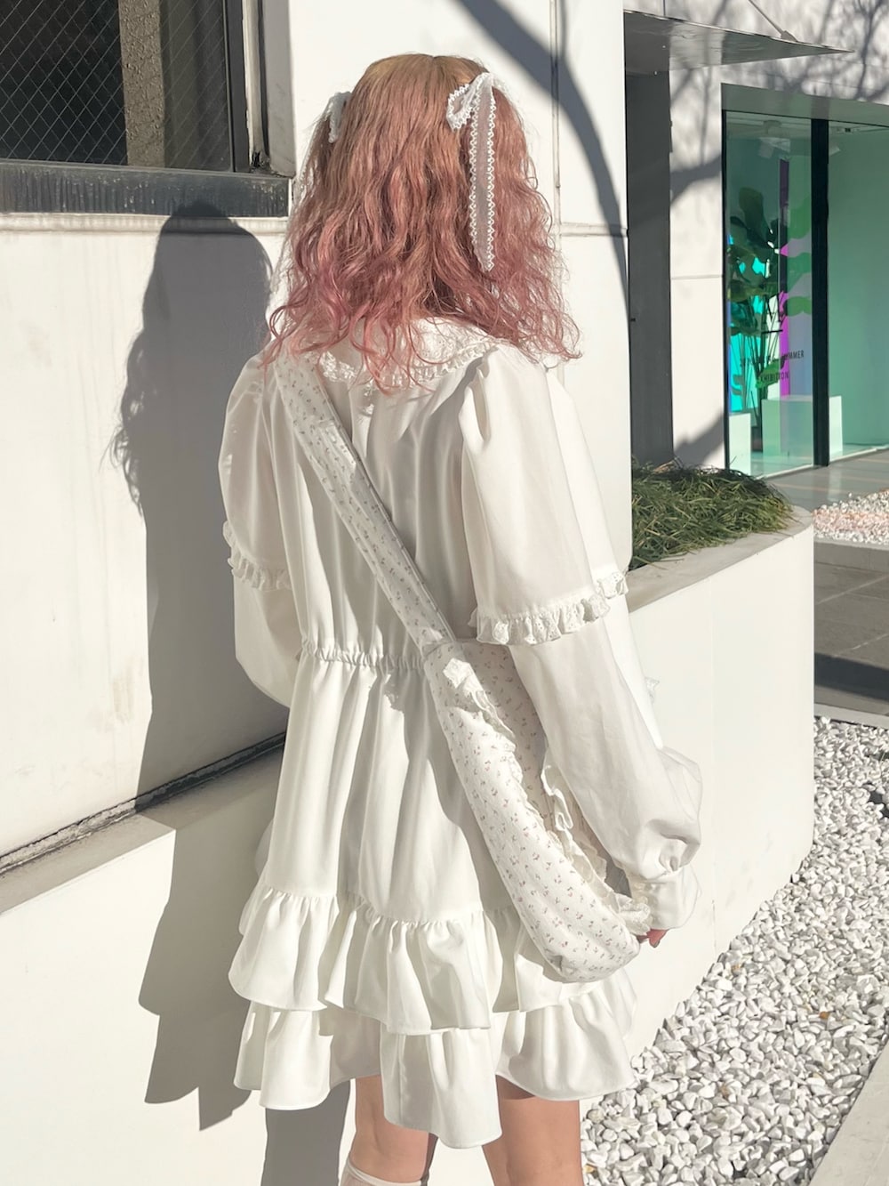 ホワイト系のワンピース、ピンク系のショルダーバッグ、ホワイト系のスニーカーを着用したレディースの冬コーディネートの6枚目の写真