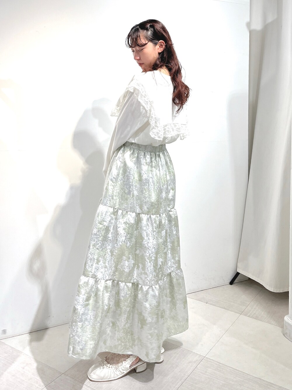 ホワイト系のTシャツ/カットソー、グリーン系のスカート、ホワイト系のパンプスを着用したレディースの冬コーディネートの3枚目の写真