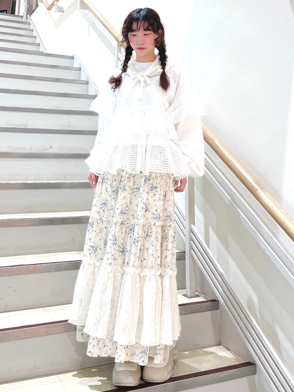 ホワイト系のスウェット、ブルー系のスカート、ホワイト系のスニーカーを着用したレディースの冬コーディネートの2枚目の写真