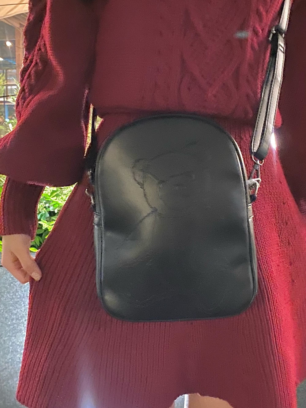 レッド系のワンピース、ブラック系のショルダーバッグ、ブラック系のブーツを着用したレディースの秋コーディネートの4枚目の写真