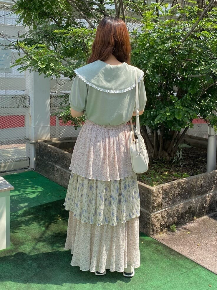 ホワイト系のスカート、ホワイト系のサンダル、グリーン系のTシャツ/カットソーを着用したレディースの夏コーディネートの2枚目の写真