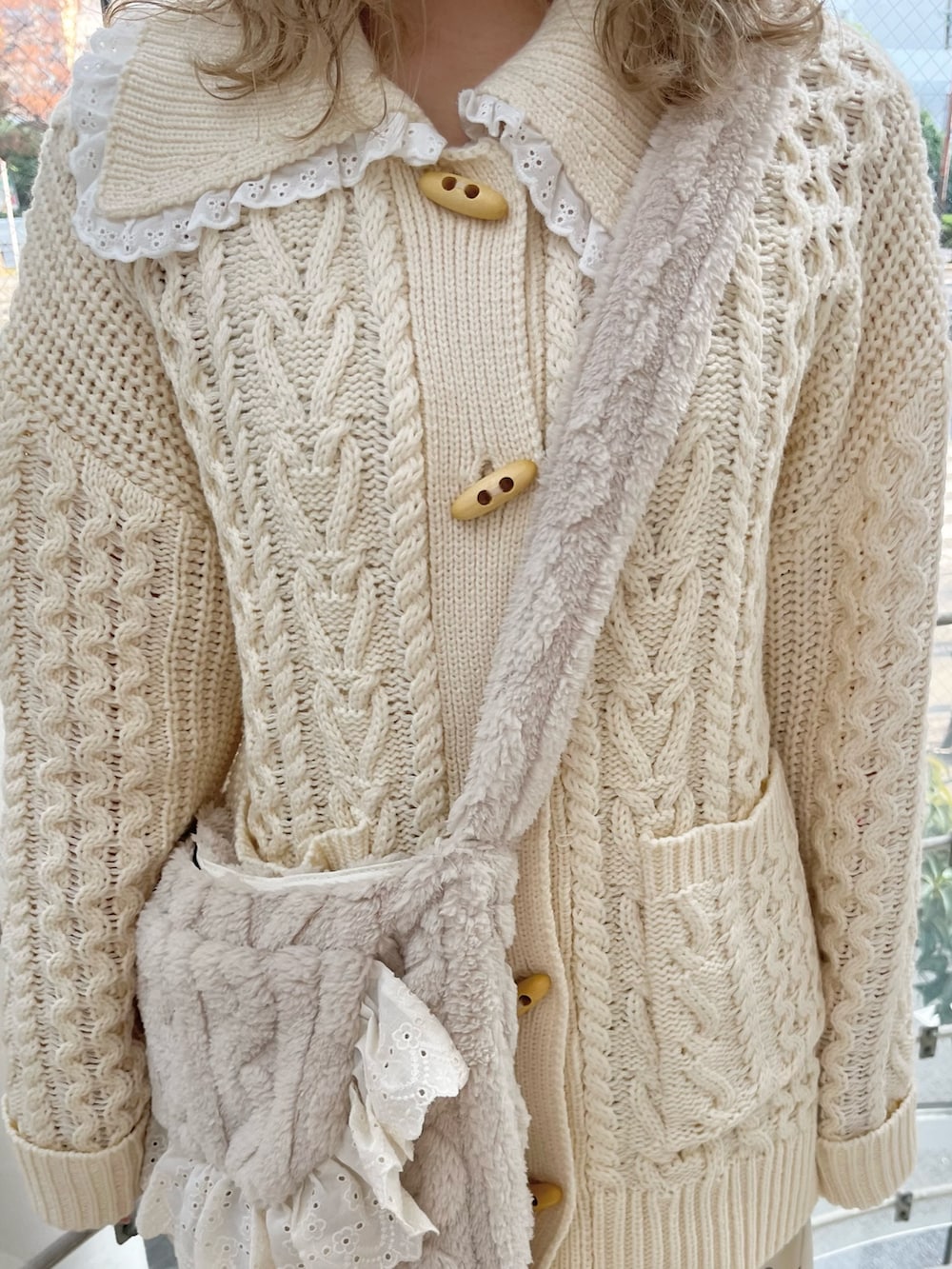 ホワイト系のカーディガン/ボレロ、ホワイト系のスカート、ベージュ系のショルダーバッグを着用したレディースの冬コーディネートの7枚目の写真