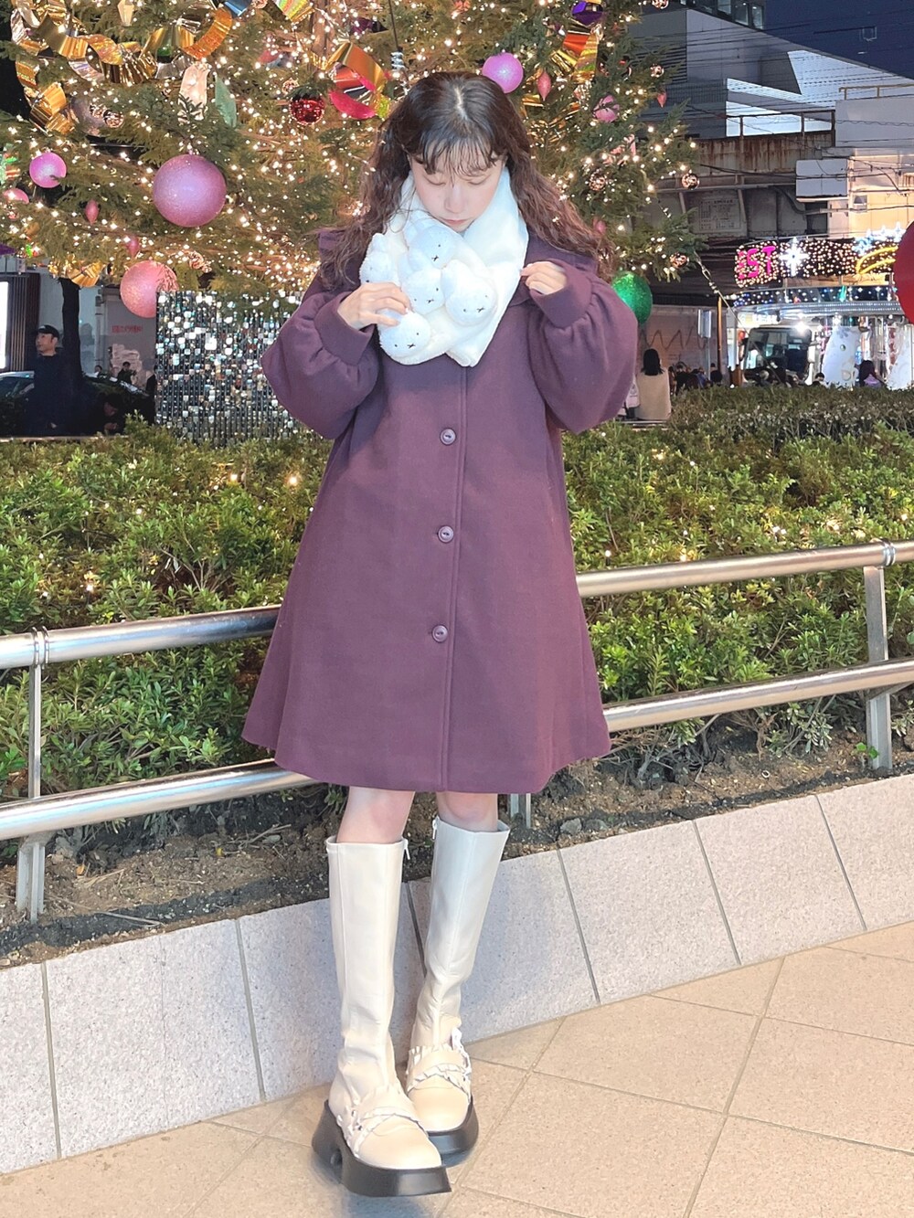 レッド系のチェスターコート、ホワイト系のニット/セーター、ホワイト系のスウェットを着用したレディースの冬コーディネートの2枚目の写真