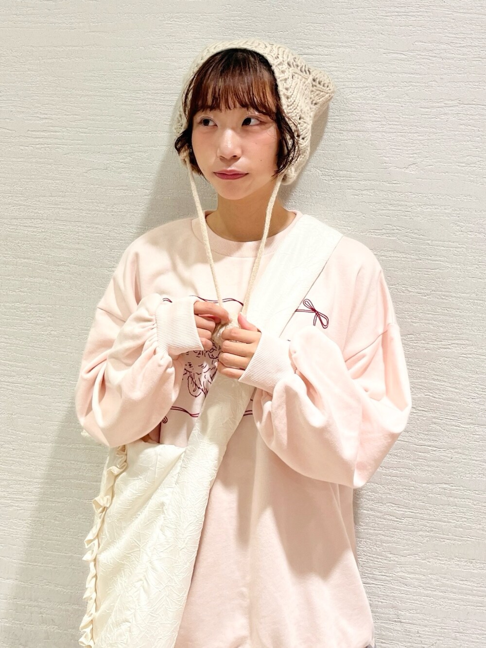 ピンク系のスウェット、ベージュ系のスカート、ホワイト系のトートバッグを着用したレディースの秋コーディネートの4枚目の写真