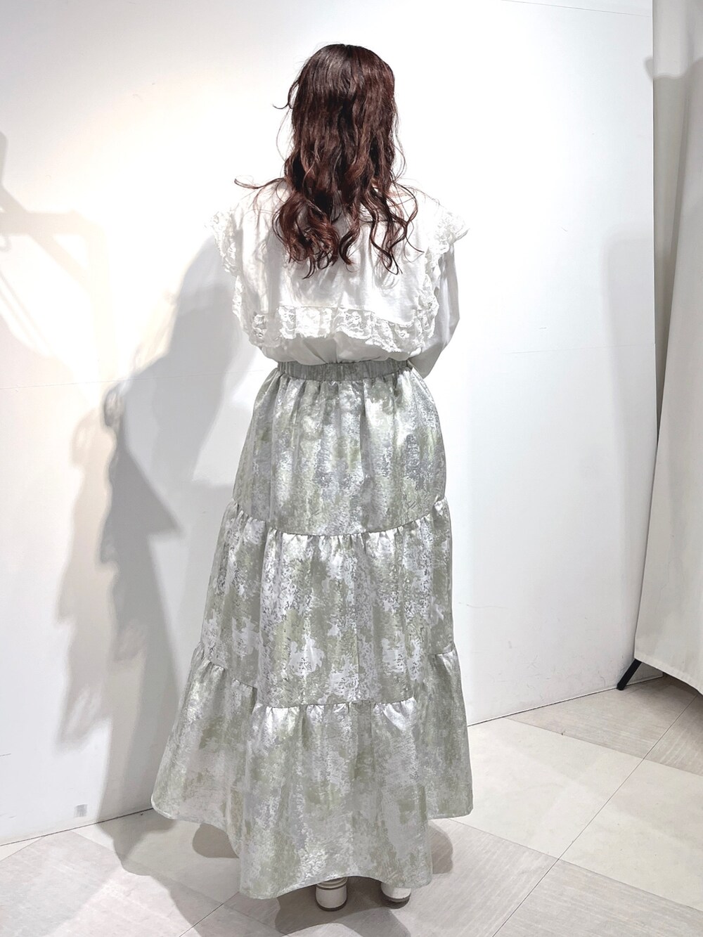 ホワイト系のTシャツ/カットソー、グリーン系のスカート、ホワイト系のパンプスを着用したレディースの冬コーディネートの4枚目の写真