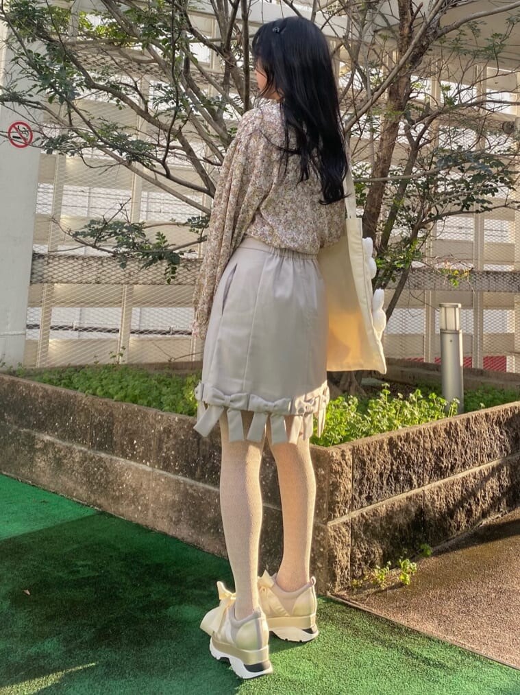 イエロー系のシャツ/ブラウス、ベージュ系のスカート、ホワイト系のスニーカーを着用したレディースの冬コーディネートの3枚目の写真