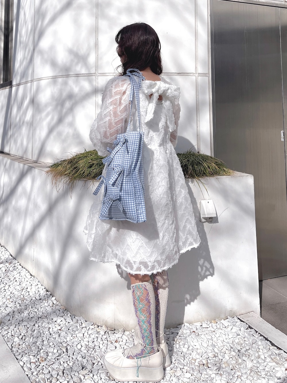 ホワイト系のワンピース、ブルー系のトートバッグ、ホワイト系のバレエシューズを着用したレディースの冬コーディネートの4枚目の写真