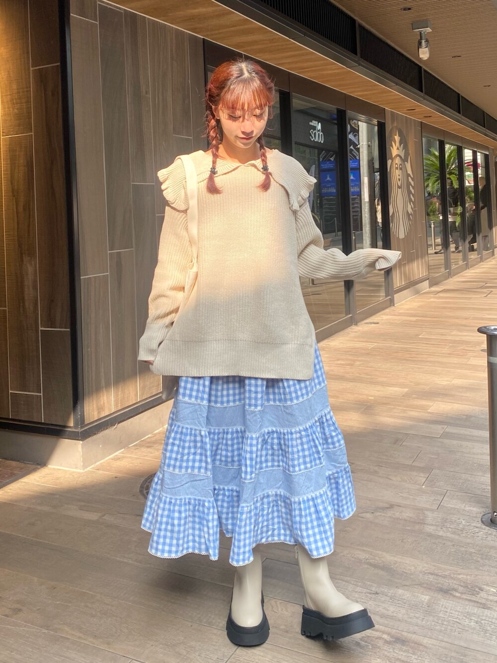 ホワイト系のニット/セーター、ホワイト系のトートバッグ、ブルー系のスカートを着用したレディースの冬コーディネートの2枚目の写真