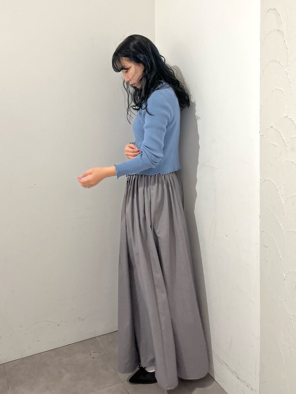 ブルー系のニット/セーター、グレー系のスカート、ブラック系のパンプスを着用したレディースの春コーディネートの3枚目の写真