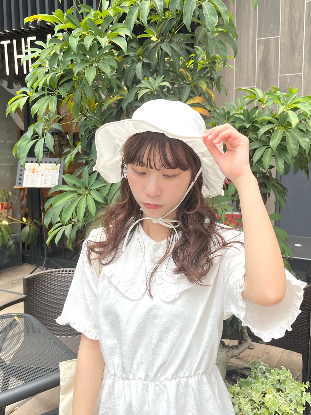 ホワイト系のスニーカー、ホワイト系のワンピース、ホワイト系のトートバッグを着用したレディースの夏コーディネートの3枚目の写真