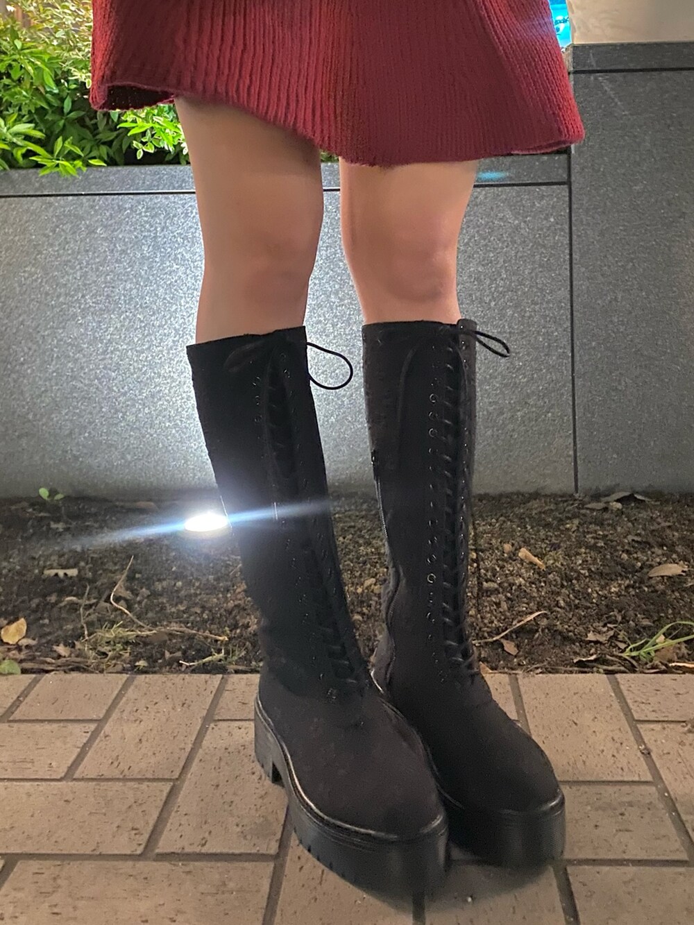 レッド系のワンピース、ブラック系のショルダーバッグ、ブラック系のブーツを着用したレディースの秋コーディネートの5枚目の写真