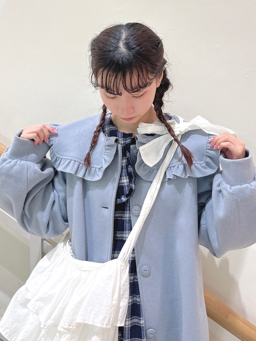 ブルー系のチェスターコート、ブルー系のワンピース、ホワイト系のショルダーバッグを着用したレディースの冬コーディネートの5枚目の写真