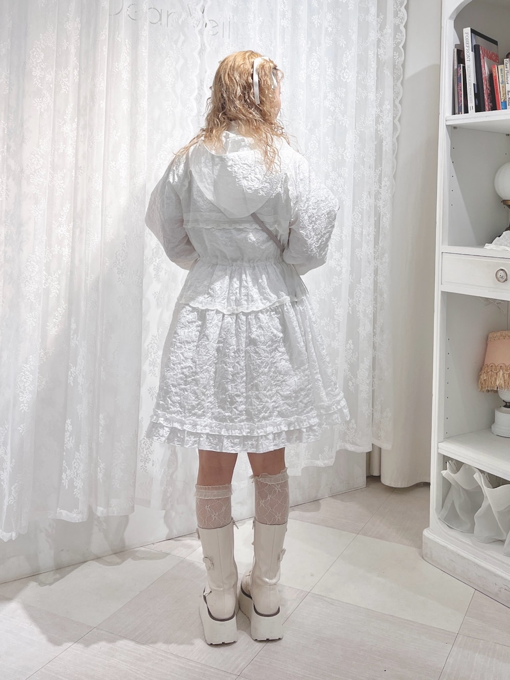 ホワイト系のワンピース、ピンク系のハンドバッグ、ホワイト系のブーツを着用したレディースの夏コーディネートの3枚目の写真