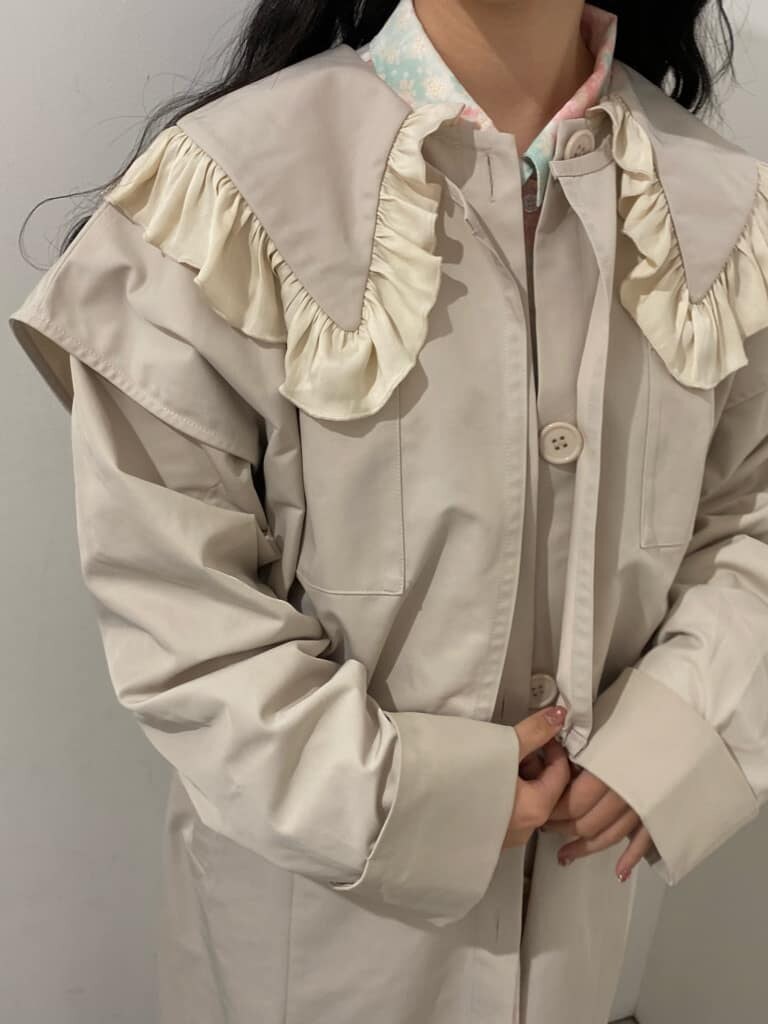 ホワイト系のトレンチコート、ピンク系のワンピース、ホワイト系のスニーカーを着用したレディースの冬コーディネートの5枚目の写真