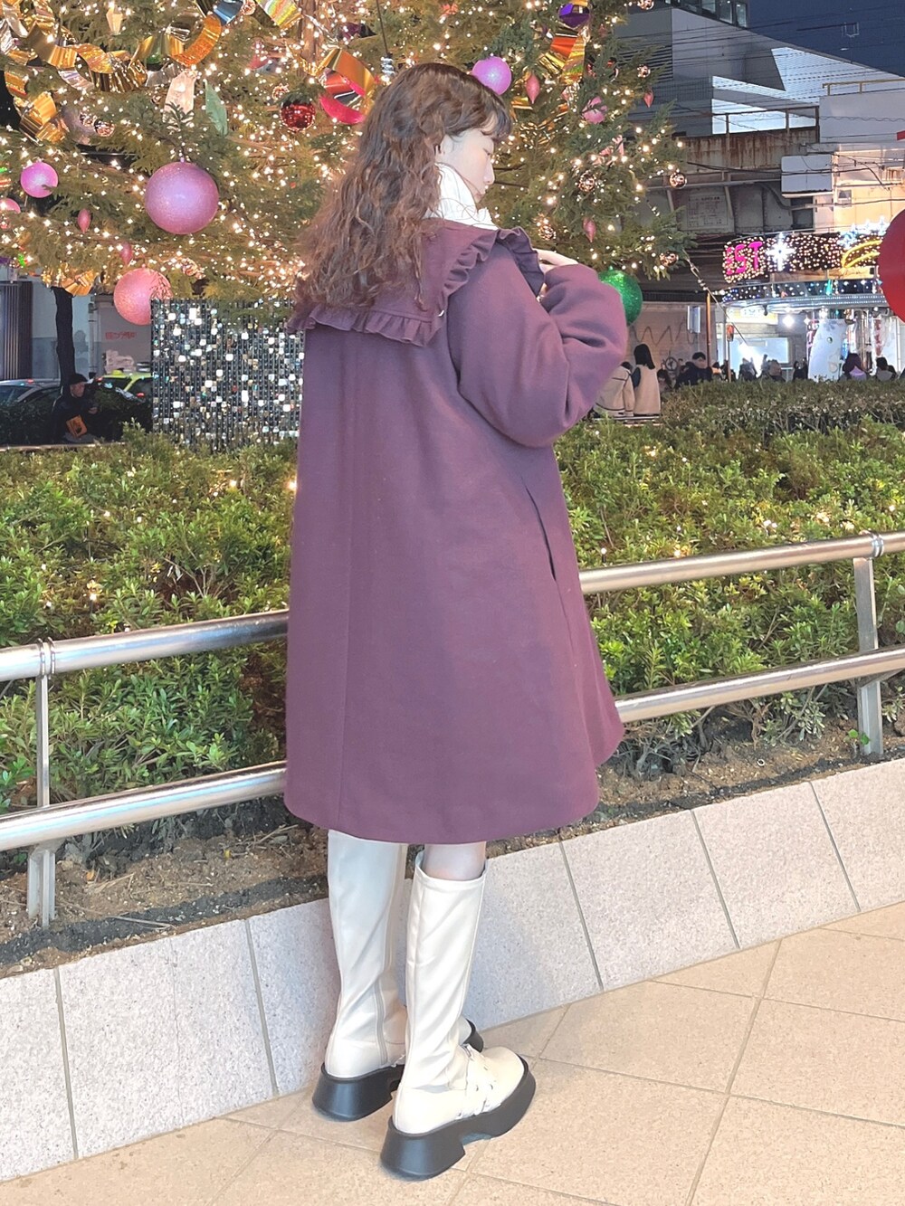 レッド系のチェスターコート、ホワイト系のニット/セーター、ホワイト系のスウェットを着用したレディースの冬コーディネートの3枚目の写真