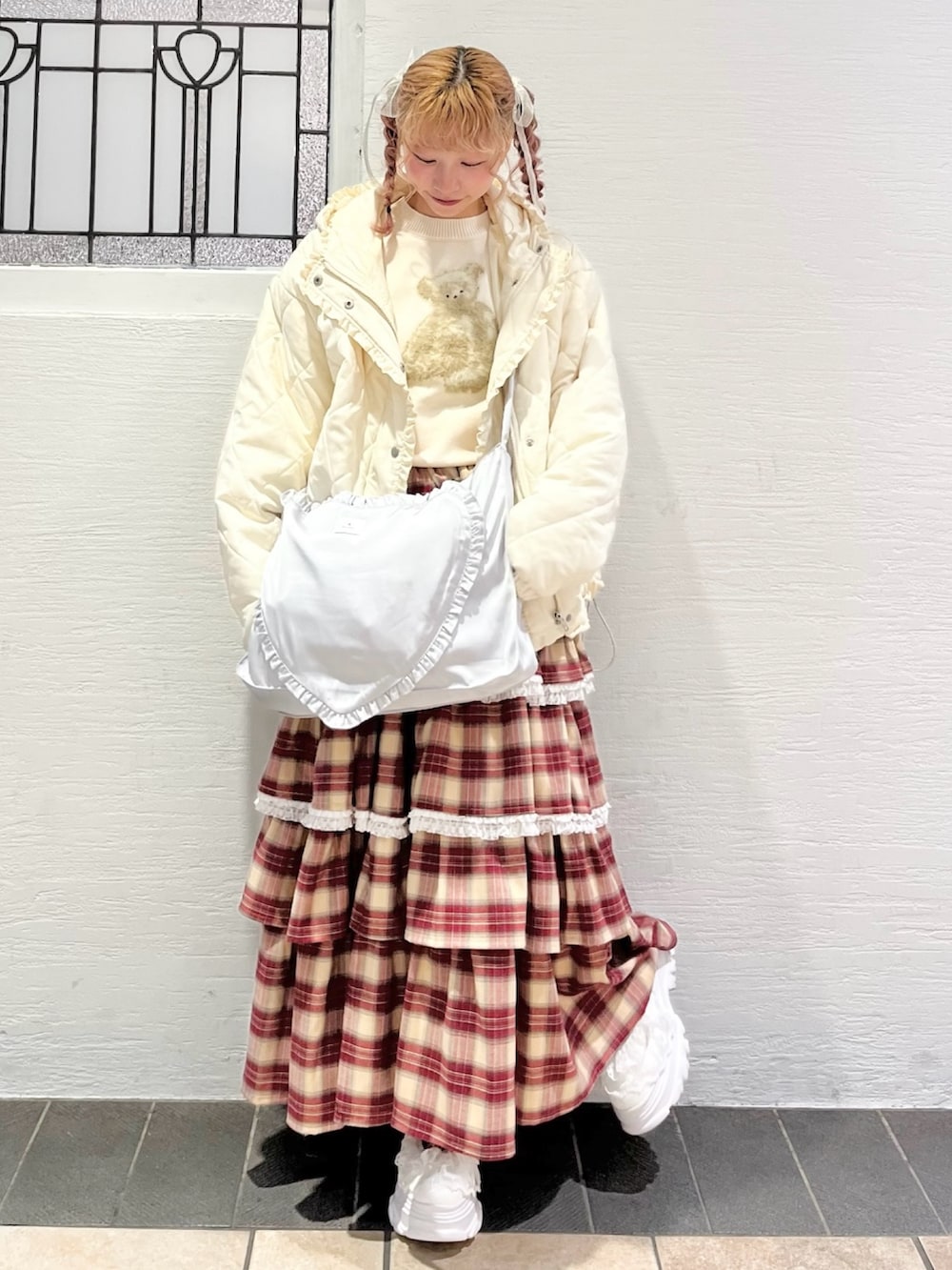 ホワイト系のダウンジャケット/コート、ホワイト系のニット/セーター、ブルー系のショルダーバッグを着用したレディースの冬コーディネートの2枚目の写真