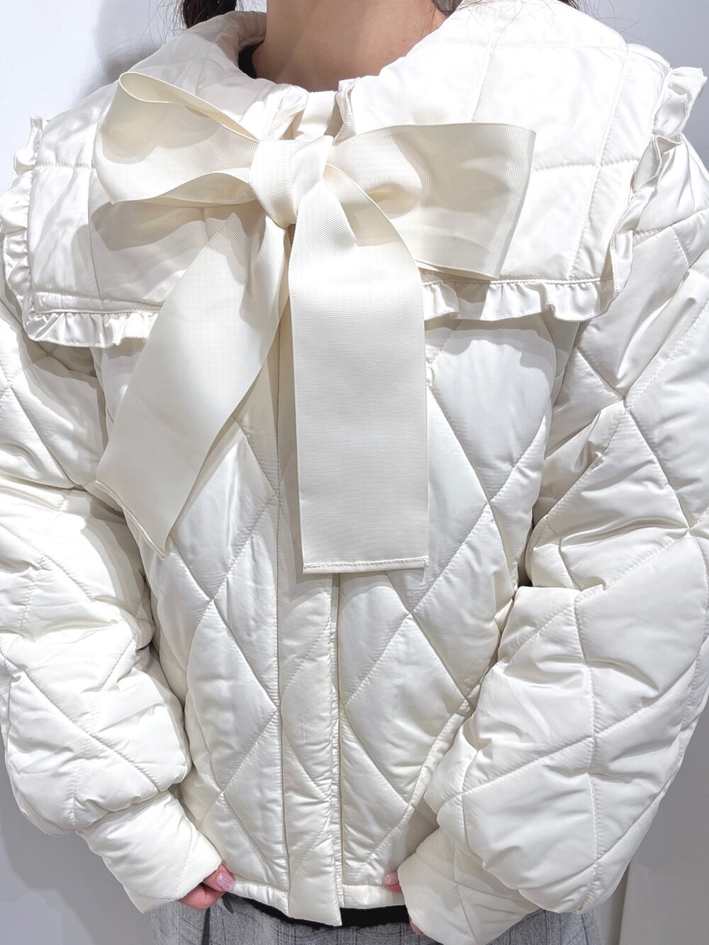 ブラック系のニット/セーター、ホワイト系のダウンジャケット/コート、グレー系のスカートを着用したレディースの冬コーディネートの4枚目の写真