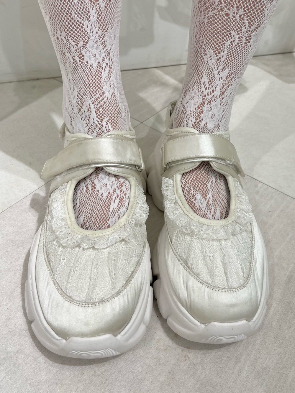 グリーン系のカーディガン/ボレロ、グレー系のスカート、ホワイト系のスニーカーを着用したレディースの秋コーディネートの6枚目の写真