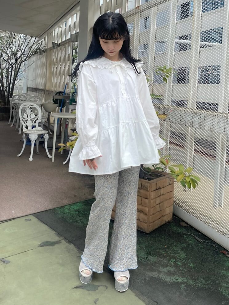 グレー系のサンダル、ホワイト系のチュニック、ブルー系のその他パンツを着用したレディースの秋コーディネートの2枚目の写真