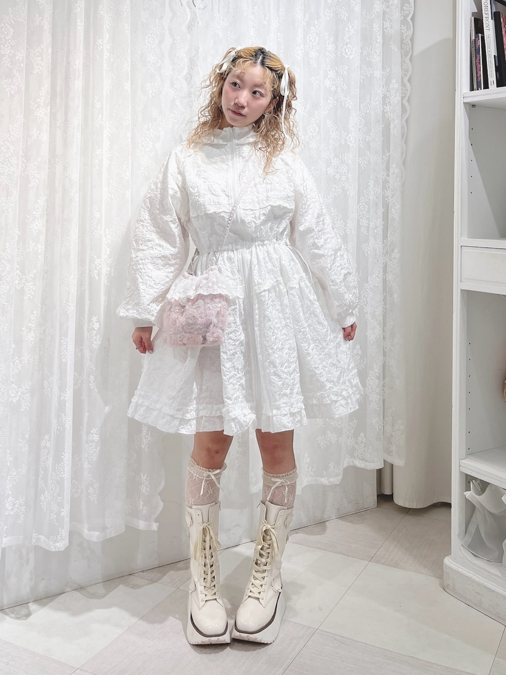 ホワイト系のワンピース、ピンク系のハンドバッグ、ホワイト系のブーツを着用したレディースの夏コーディネートの2枚目の写真