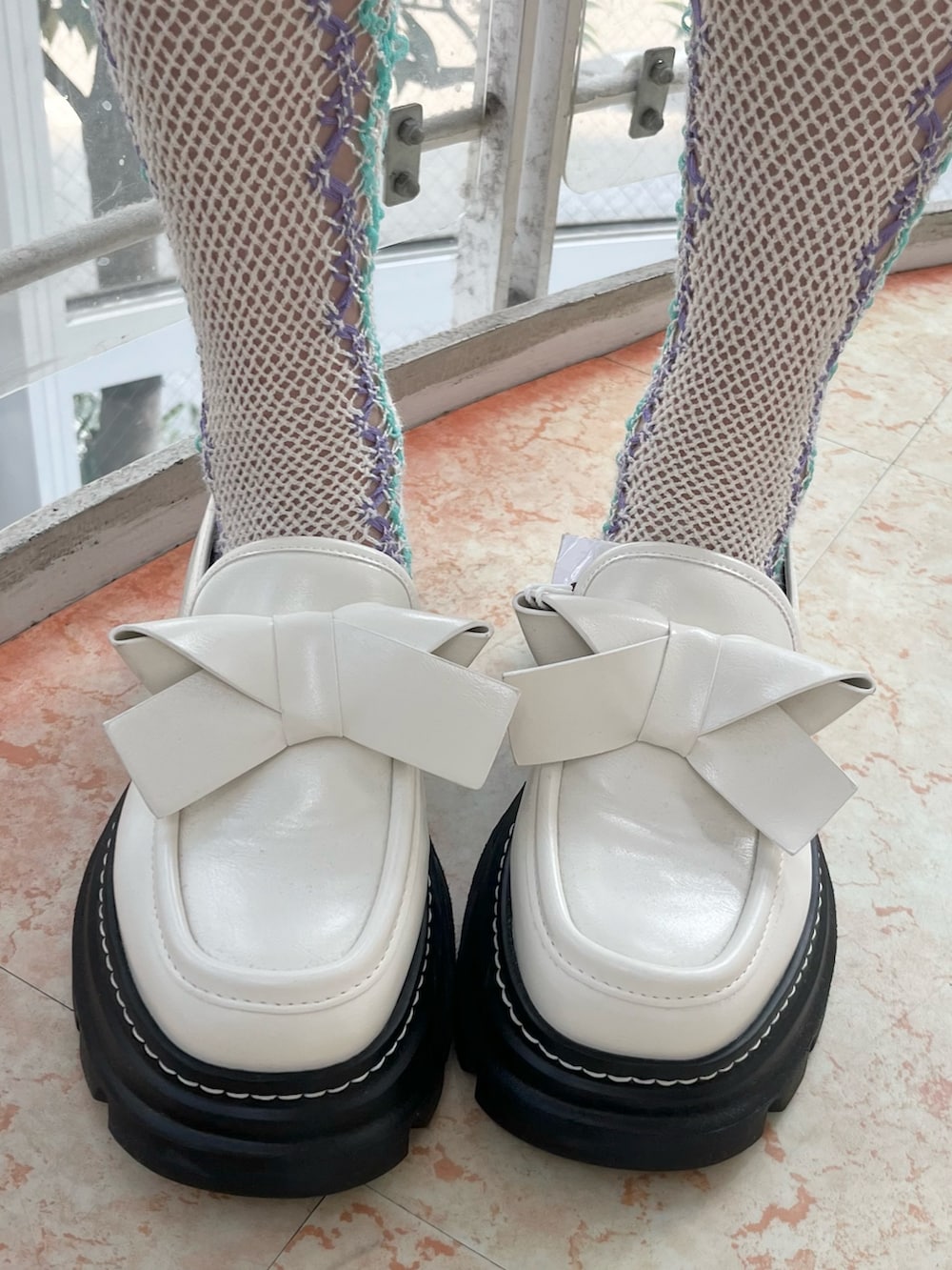 ホワイト系のカーディガン/ボレロ、ホワイト系のスカート、ベージュ系のショルダーバッグを着用したレディースの冬コーディネートの10枚目の写真