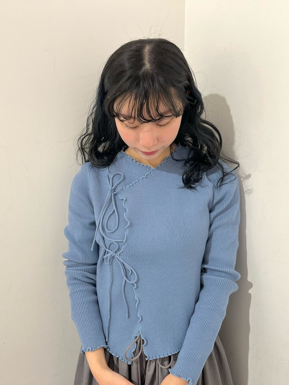 ブルー系のニット/セーター、グレー系のスカート、ブラック系のパンプスを着用したレディースの春コーディネートの5枚目の写真