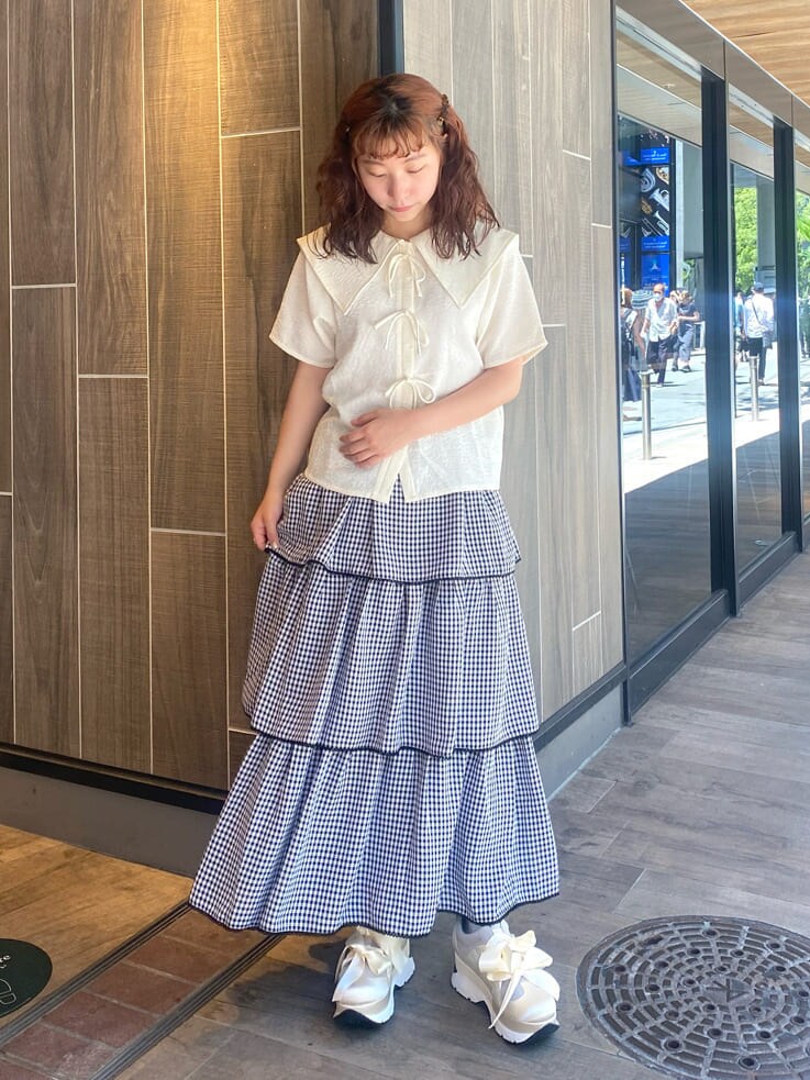 ホワイト系のスニーカー、ブラック系のスカート、ホワイト系のシャツ/ブラウスを着用したレディースの夏コーディネートの2枚目の写真