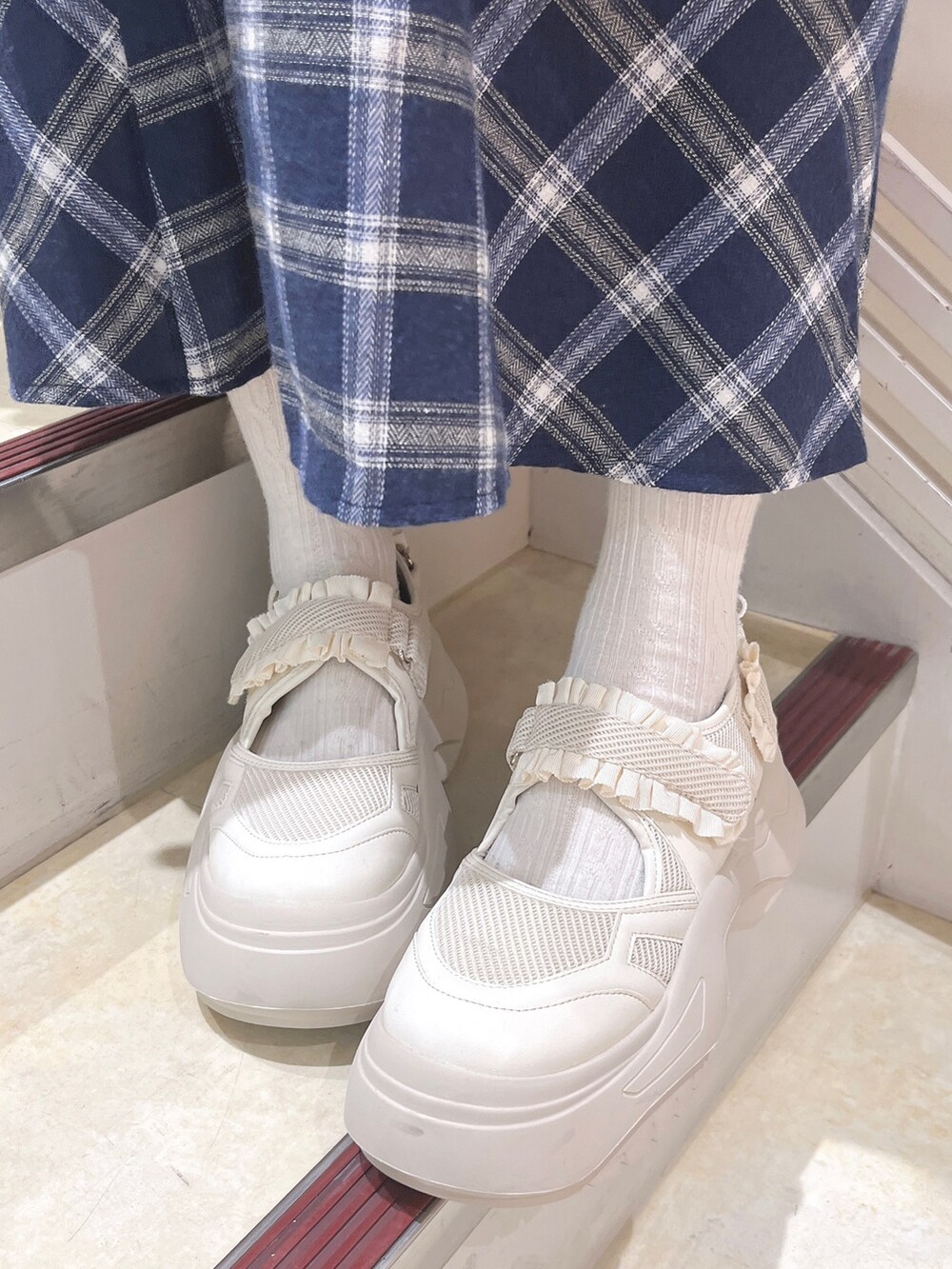 ブルー系のチェスターコート、ブルー系のワンピース、ホワイト系のショルダーバッグを着用したレディースの冬コーディネートの10枚目の写真