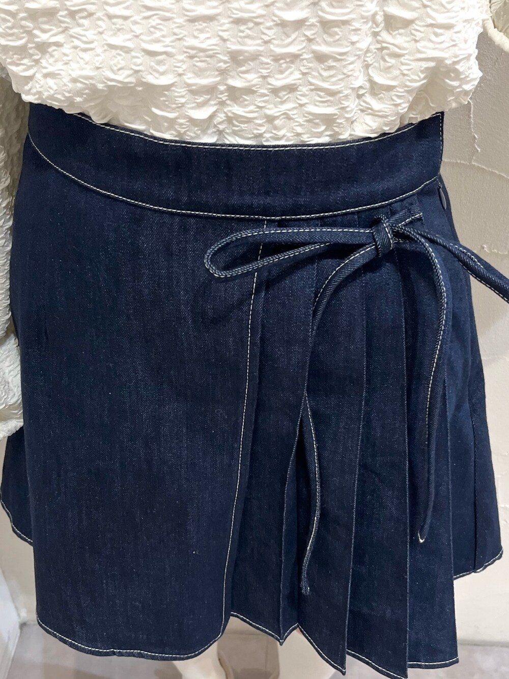 ブルー系のデニムスカート、ホワイト系のTシャツ/カットソー、ホワイト系のスニーカーを着用したレディースの冬コーディネートの7枚目の写真