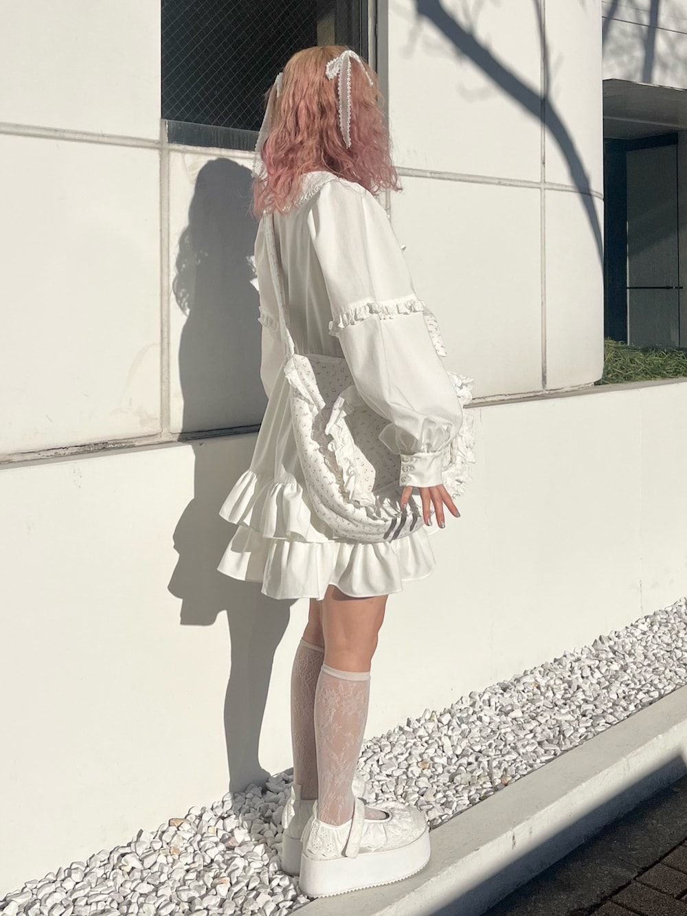 ホワイト系のワンピース、ピンク系のショルダーバッグ、ホワイト系のスニーカーを着用したレディースの冬コーディネートの2枚目の写真