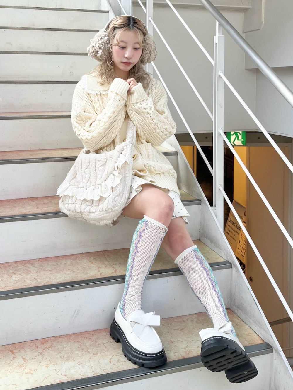 ホワイト系のカーディガン/ボレロ、ホワイト系のスカート、ベージュ系のショルダーバッグを着用したレディースの冬コーディネートの4枚目の写真