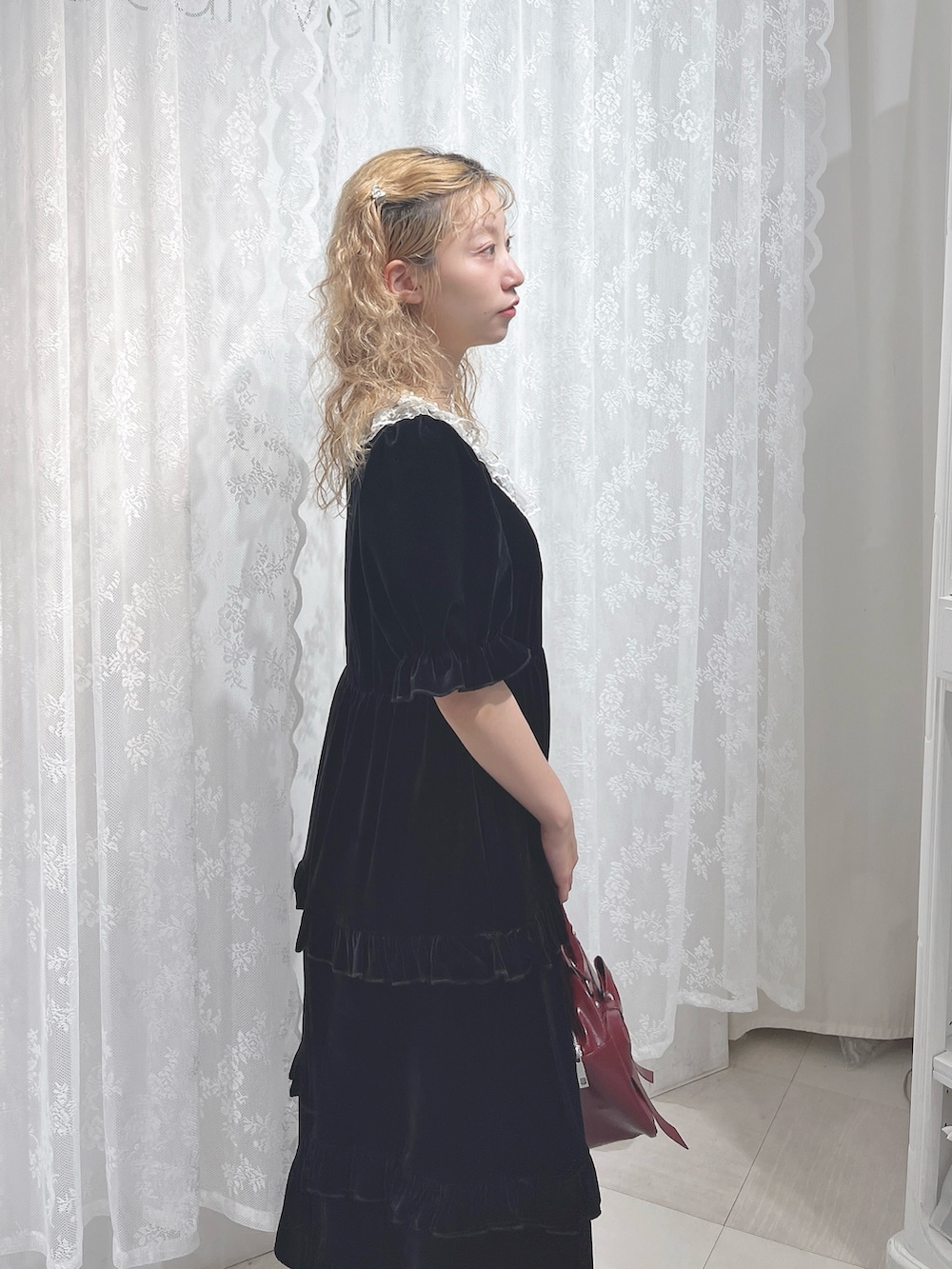 ブラック系のワンピース、レッド系のハンドバッグ、ブラック系のパンプスを着用したレディースの夏コーディネートの5枚目の写真