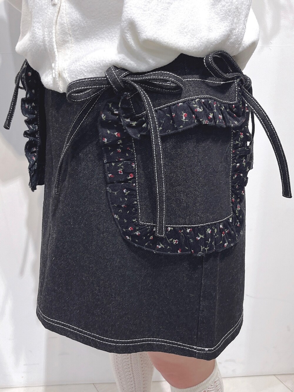 ホワイト系のカーディガン/ボレロ、ブラック系のデニムスカート、ブラック系のスニーカーを着用したレディースの冬コーディネートの9枚目の写真