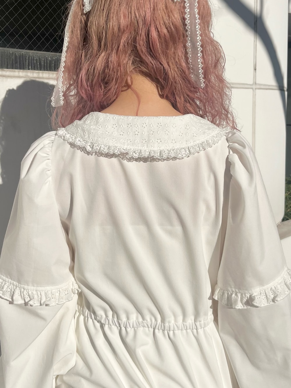 ホワイト系のワンピース、ピンク系のショルダーバッグ、ホワイト系のスニーカーを着用したレディースの冬コーディネートの8枚目の写真