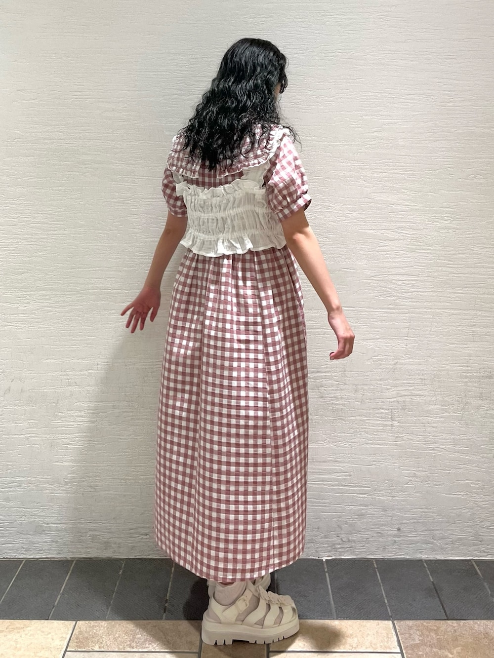 ピンク系のワンピース、ホワイト系のサンダル、ホワイト系のベストを着用したレディースの夏コーディネートの3枚目の写真